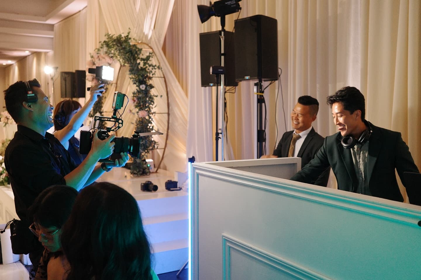 The Radiate DJ and MC team behind a white booth at a wedding reception